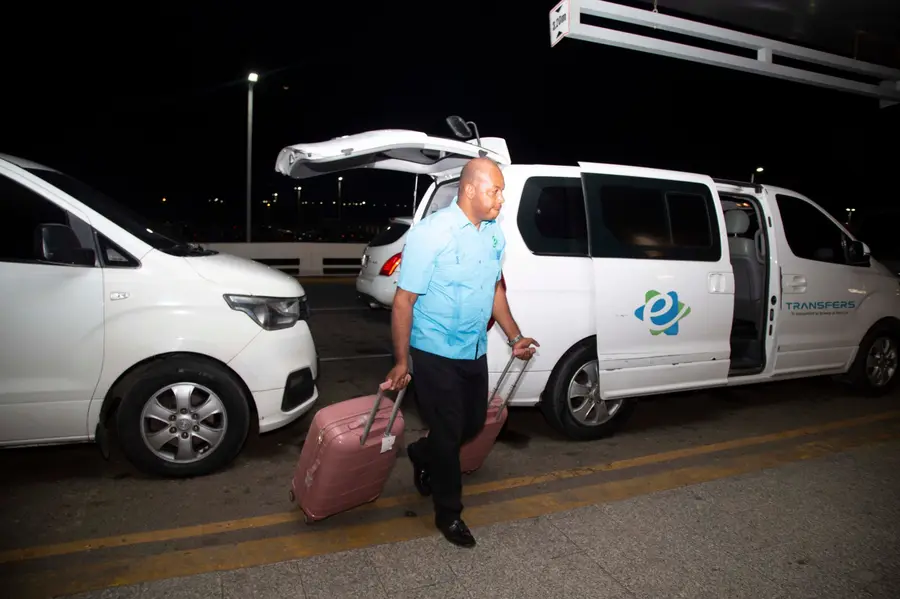 Capitán de eTransferSDQ baja las maletas de los clientes junto a la van en el aeropuerto